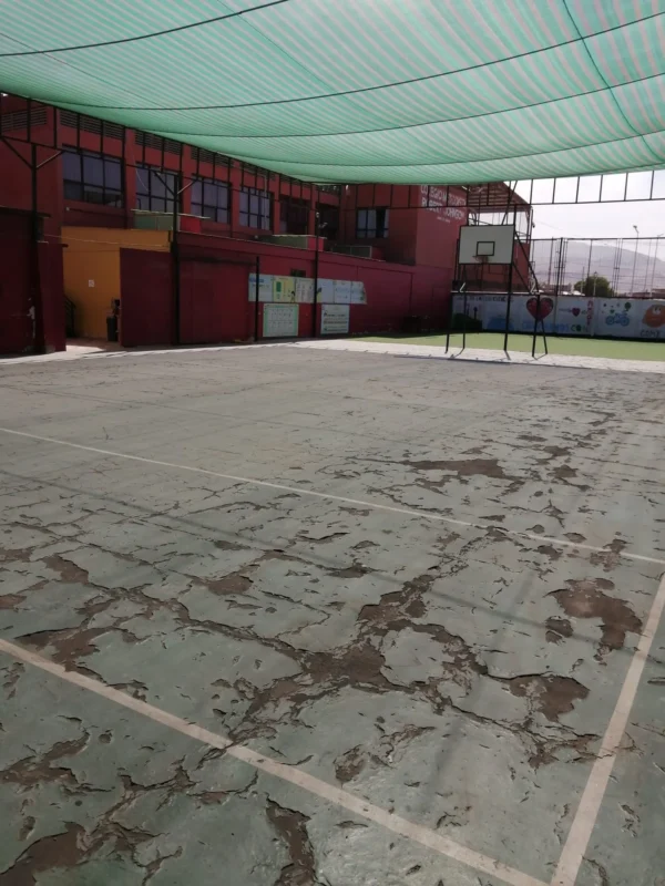 Multicancha techada del Colegio Metodista Robert Johnson antes, con la superficie antigua agrietada y desprendida