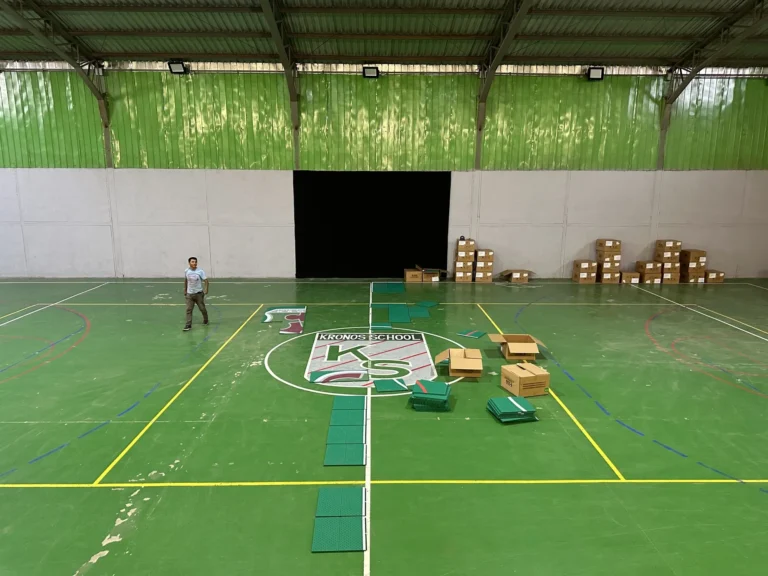 Armado del logo del Liceo Bicentenario Kronos con baldosas de colores durante la instalación del gimnasio