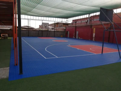Multicancha techada del Colegio Metodista Robert Johnson después, con piso modular azul y rojo y demarcación de básquetbol
