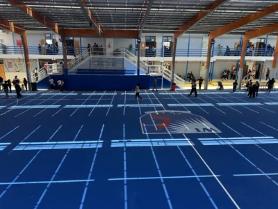 Alumnos del Colegio William Taylor usando la multicancha techada renovada, con el logo del colegio en el piso