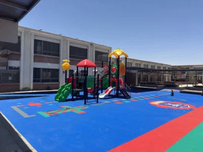 Patio del Colegio Maristas después, con piso modular azul y juegos infantiles